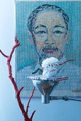 Asiatische Tischdeko: Rotgefärbter Zweig und Tischleuchte mit Buch als schwebendes Tablett vor grossformatigem Portrait