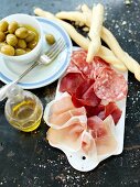 Ham and salami with olives and grissini
