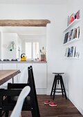Black, child's chair at table and old swivel stool in background next to hatch in modern, white interior