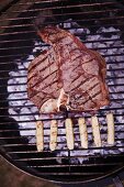 A T-bone steak and sausages on a barbecue