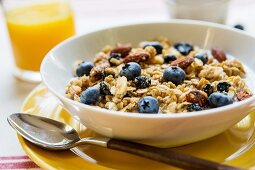 Frühstücksmüsli mit frischen Blaubeeren; dazu Orangensaft