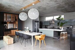 Blick in offenen Designer-Küchen-Essbereich mit puristischem elegantem Holz-Einbauregal als Raumteiler, Betondecke mit zwei Pendel-Kugelleuchten