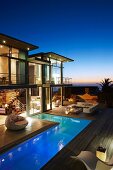Luxushaus mit L-förmigem Pool und Terrasse beleuchtet in märchenhafter Abendstimmung mit Meerblick