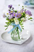 Posy in jar on heart-shaped dish on wedding reception table