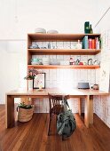 Wooden table under shelves with dishes on wooden floor