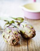Two artichokes on a wooden surface