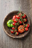 Various freshly washed tomatoes in a wooden bowl