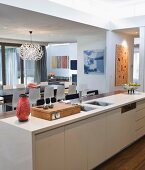 Blick von Küchentheke mit Dekoobjekten aus den 60er Jahren auf offenen Wohnraum mit Designerleuchte Dandelion über dem Esstisch