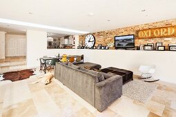 Extended, open-plan, modern living area with exposed brickwork, stone flagged floor and view into raised kitchen