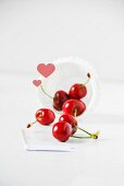 Red cherries falling out of a paper case with hearts