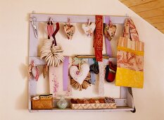 Heart-shaped pincushions made from vintage, French fabrics, fabric bag and ribbons hanging on old wooden rack