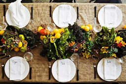 Set table decorated with centrepiece of fruit, vegetables & flowers