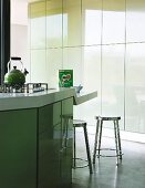 Kochinsel mit abgesenktem Thekentisch in Designerküche mit pastellgrünen Tip-On Schranktüren