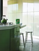 Island counter with lowered breakfast bar in designer kitchen with pastel green tip-on doors