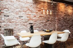 White shell chairs around dining table and simple pendant lamps in front of brick wall