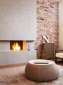 Round coffee table in front of open fireplace in concrete chimney breast set in brick wall