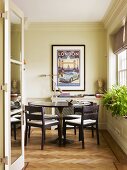 View through open glass door of round table in front of frame vintage poster in renovated period property