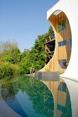 Außergewöhnliches Haus aus Holz mit Ausschnitten in vorgebauter Fassadenscheibe mit Infinity Pool und wildem Garten