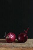 Two red onions against a dark background