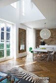 Double-height ceiling in open-plan living area with zebra-skin rug on herringbone parquet floor; dining area with classic chairs and spherical lampshade