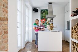 Kleine, weiße Designerküche mit Frau und Kind am zentralen Arbeitsblock