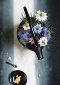 Nigella Damascena Blüten auf schwarzer gusseiserner Teekanne