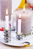 Various lit candles set on stacks or flat arrangements of bottle caps