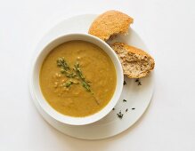 Creamer vegetable soup with thyme and a bread roll