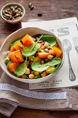 A mixed salad made with pumpkin, chickpeas, baby spinach and roasted pumpkin seeds