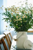 Bouquet of chamomile in white, nostalgic milk can on dining table