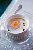 Oeuf Cocotte in an oven-proof dish on a glass plate