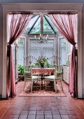 Romantic conservatory with dining table, rug and curtains
