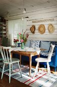 Kitchen chairs and blue bench around wooden table in rustic interior of wooden house