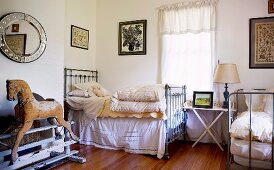 Metal beds, wooden rocking horse on old iron mechanism and collection of pictures in vintage bedroom