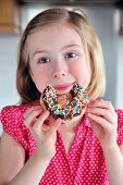 A little girl eating a doughnut with sugar sprinkles