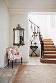 Offenes Treppenhaus einer eleganten Villa mit Polsterstuhl & Wandspiegel