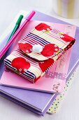 Mobile phone pouch with pattern of apples on stack of books