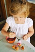 A little girl decorating mini muffins in a kitchen