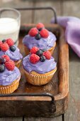 Cupcakes decorated with berry cream and fresh berries on a wooden tray
