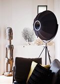 Schwarze Photolampe und afrikanische Holzskulptur, im Vordergrund Kissen auf Sofa