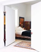 Blick durch offene Flügeltür in Schlafraum mit Bett & Schrank in asiatischem Stil