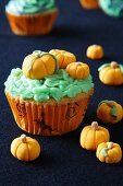 A cupcake decorated with marzipan pumpkins for Halloween