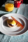 Eggs Benedict mit krusprig gebratener Parmaschinken-Scheibe auf Frühstückstisch