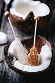 Brocken coconut with rock sugar sticks on a wooden surface