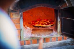 A freshly baked pizza in a wood-fired oven