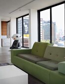 Polder sofa in shades of green and contemporary sculpture in background in front of continuous glass wall of loft apartment