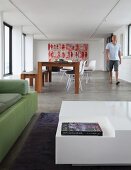 View from designer seating area to dining area with classic chairs and large modern painting on back wall of loft apartment