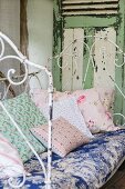 Various cushions with romantic patterns on vintage metal couch