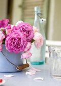 Bouquet of roses in enamel pot and glass on table