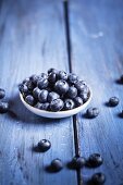 A bowl of blueberries on a blue wooden surface